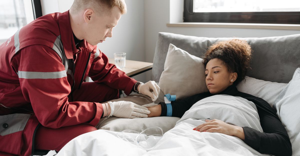 Paramedic caring for a sick woman in bed at home, highlighting home healthcare.