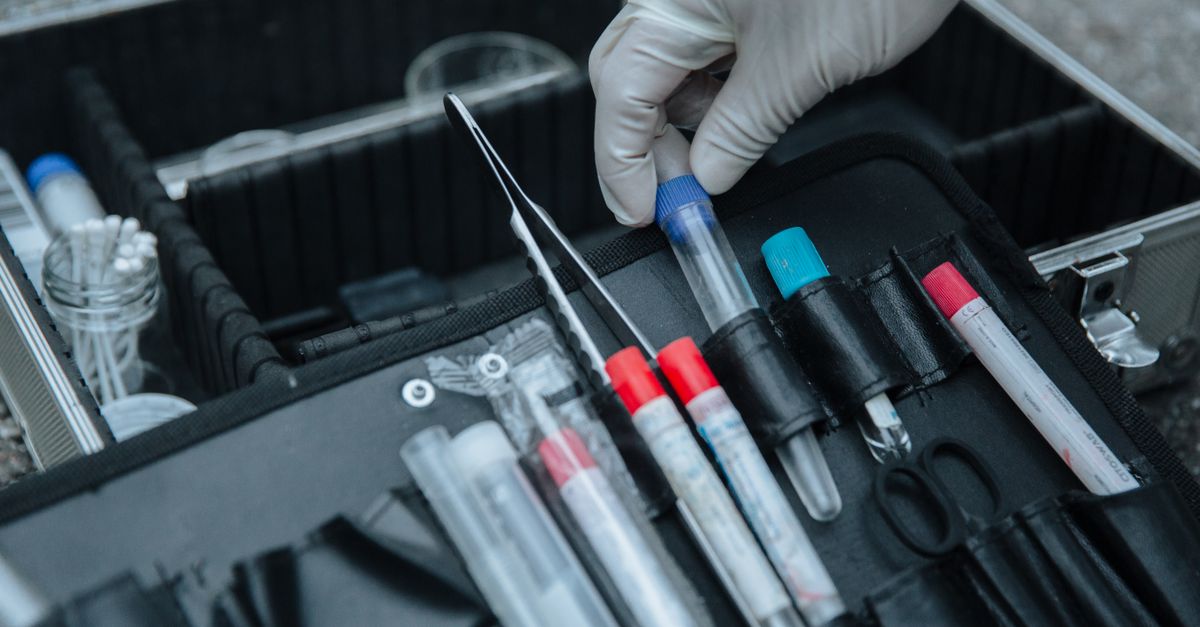 Gloved hand handling test tube in forensic equipment case at crime scene.