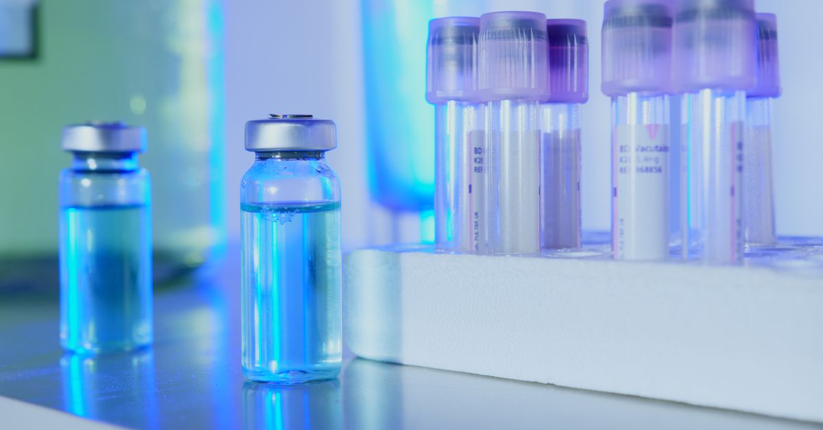 Vials and test tubes with blue liquid in a laboratory setting under fluorescent light.