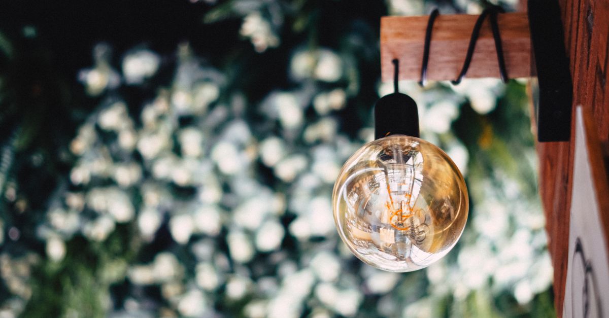 Elegant vintage light bulb hanging against a bokeh floral background, creating a warm ambiance.