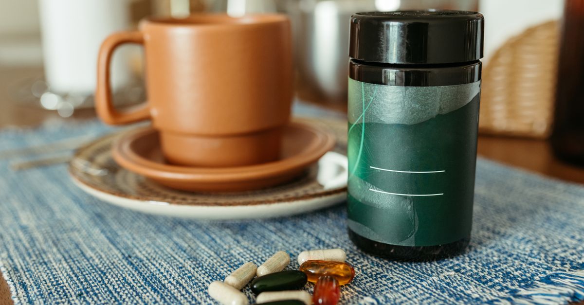 A variety of capsules near a ceramic mug and container on a table.