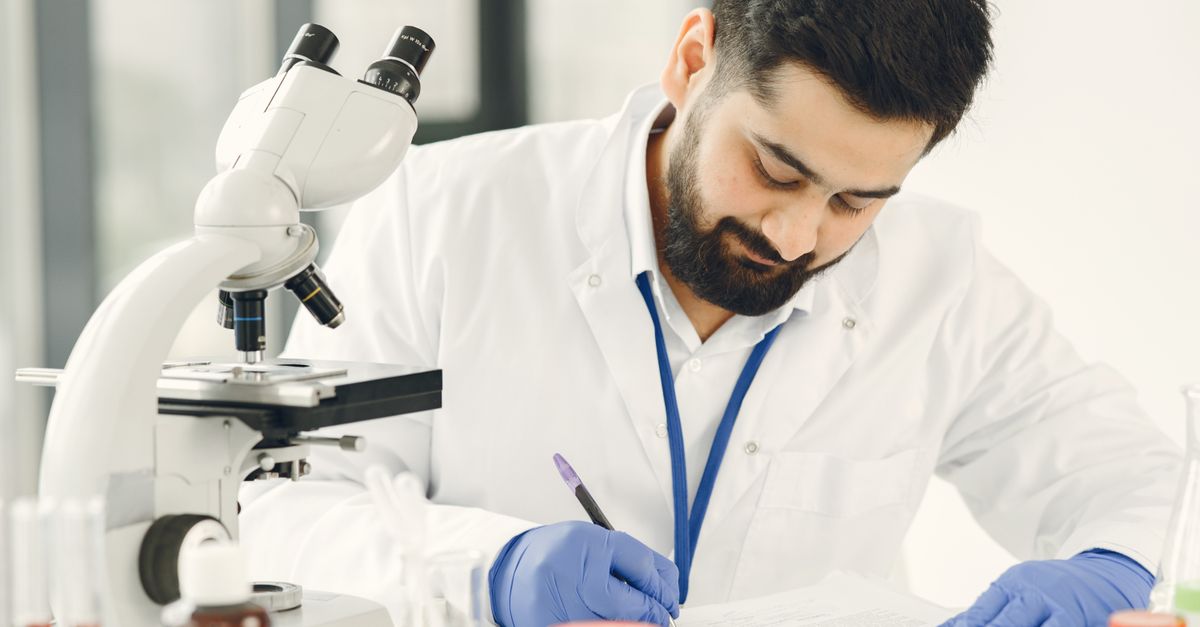Male scientist in a laboratory, examining samples and taking notes.