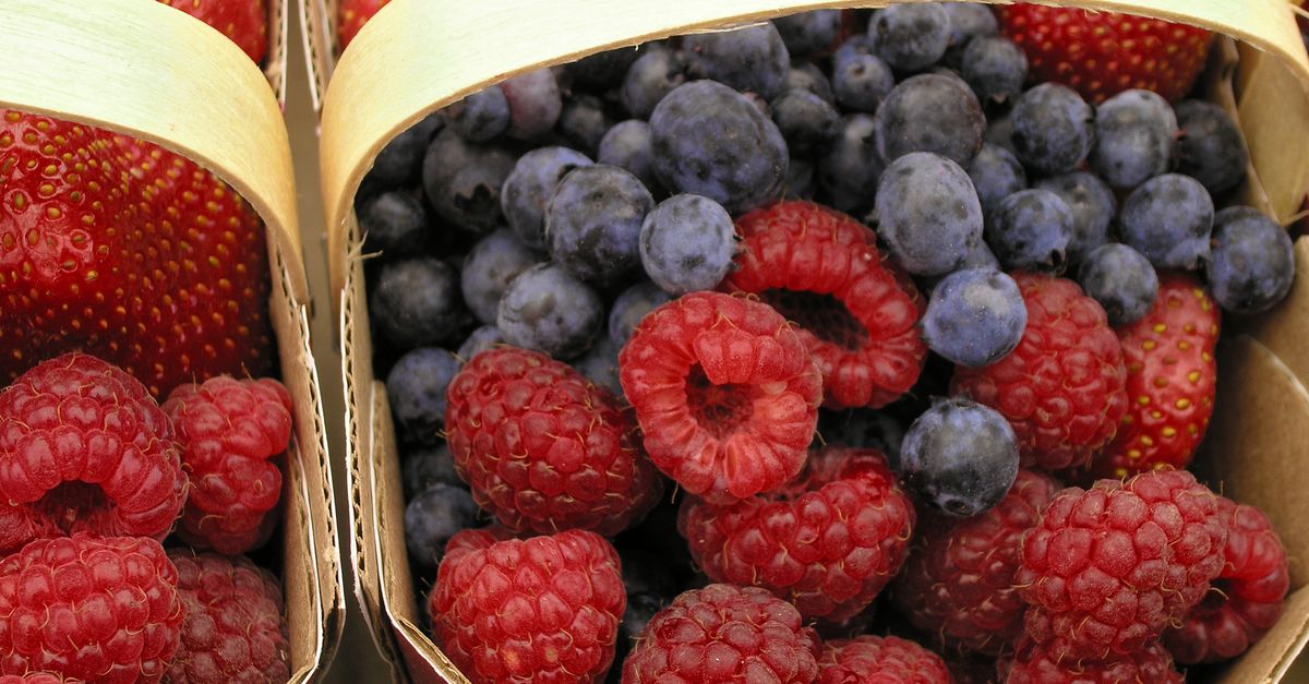 Close-up of assorted fresh berries in wooden baskets, showcasing vibrant colors.