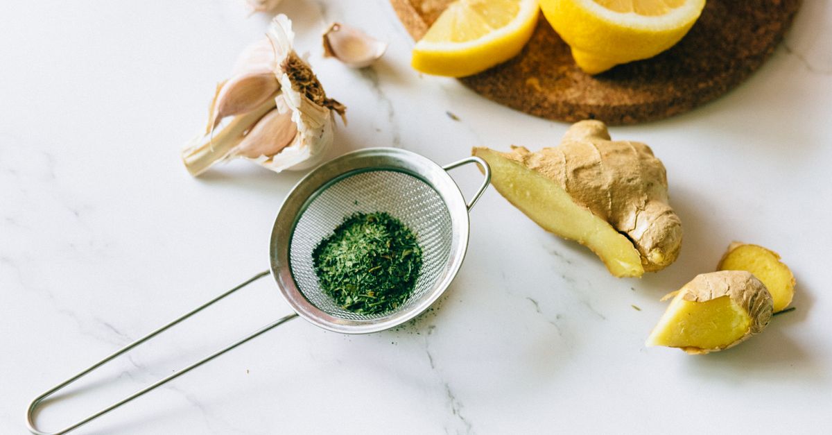 A flat lay of garlic, ginger, and lemon on a marble surface for natural remedies.