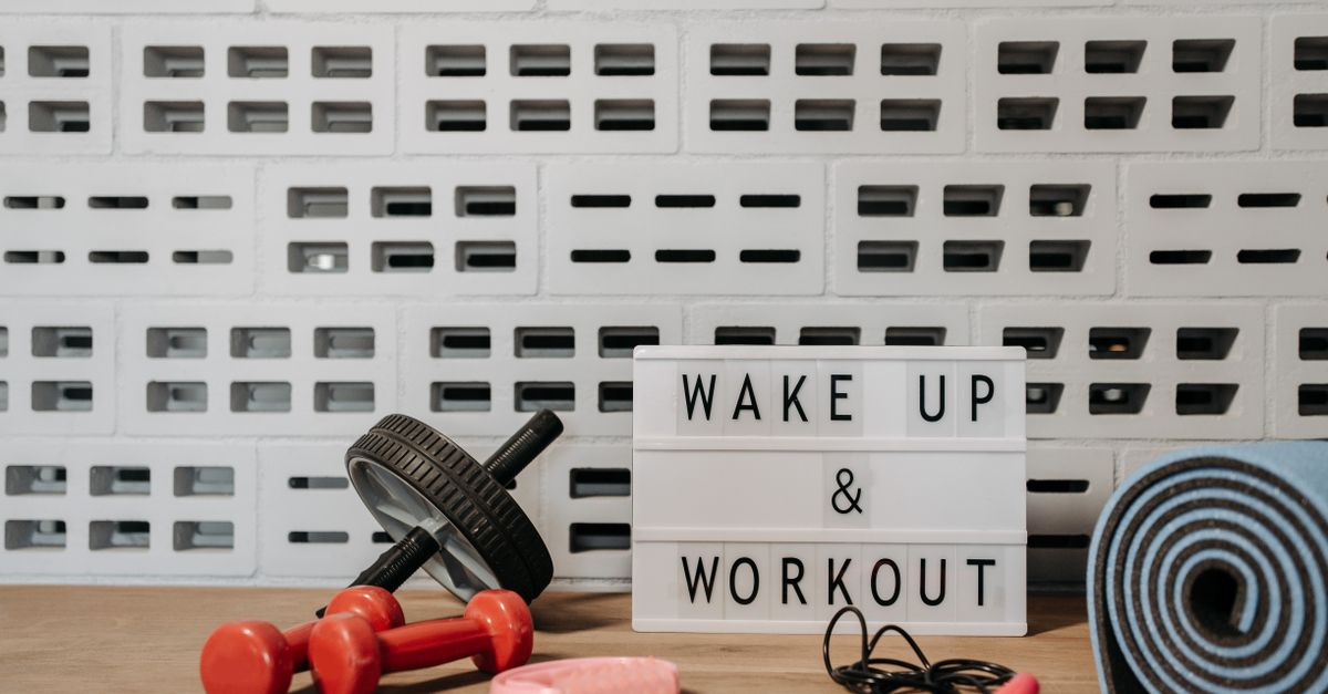 Fitness gear and motivational sign in home gym setup against a brick wall.