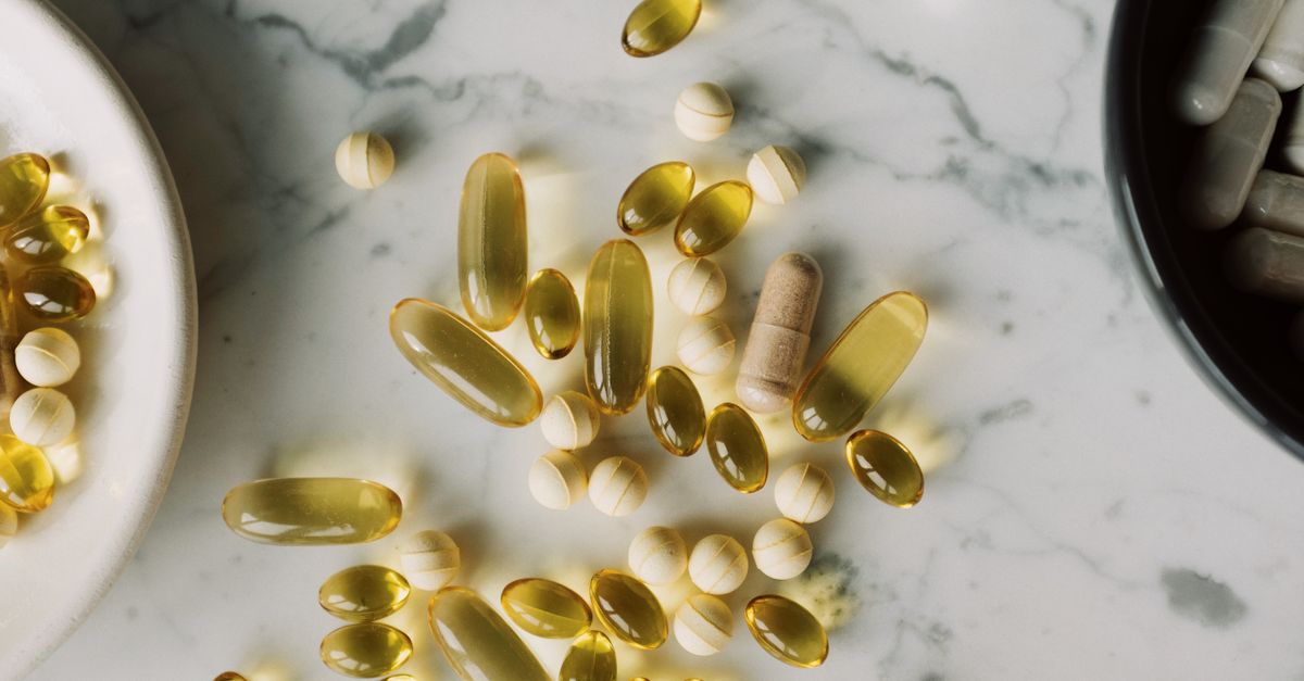 Top view of different capsules and pills placed on on desk between plates with medical remedy made to prevent vitamin deficiency