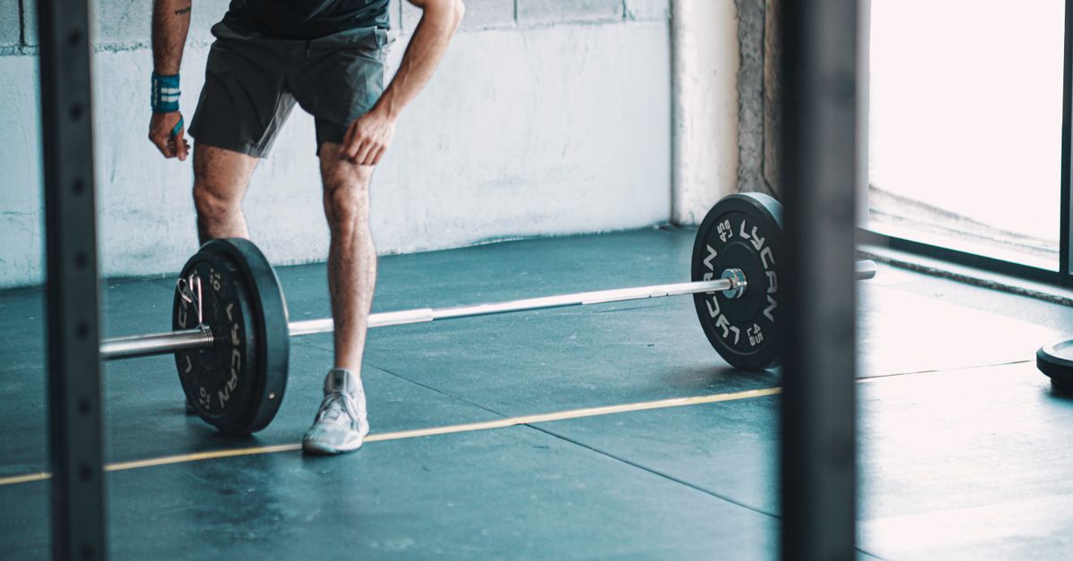 A man getting ready to lift a barbell in an indoor gym setting.