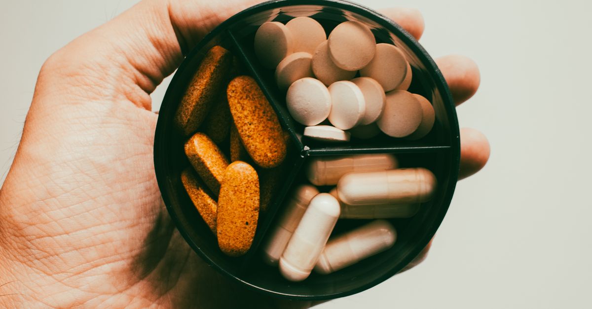 Close-up of a hand holding different types of supplements and vitamins.