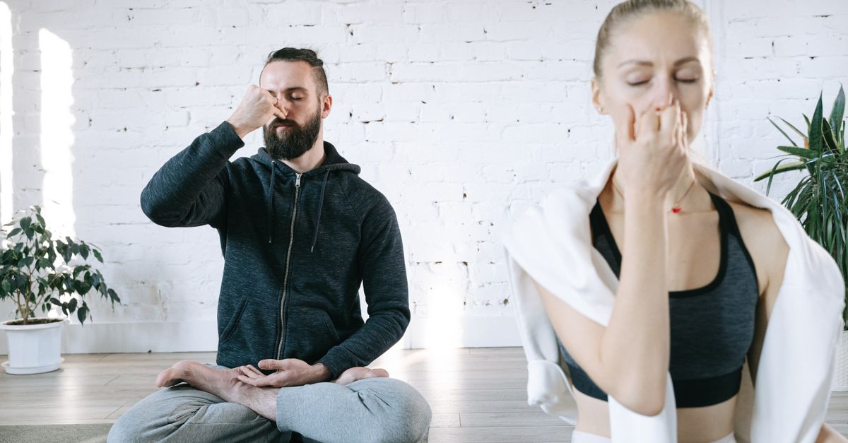 A serene couple practicing pranayama breathing techniques in a bright indoor space, fostering mindfulness and relaxation.
