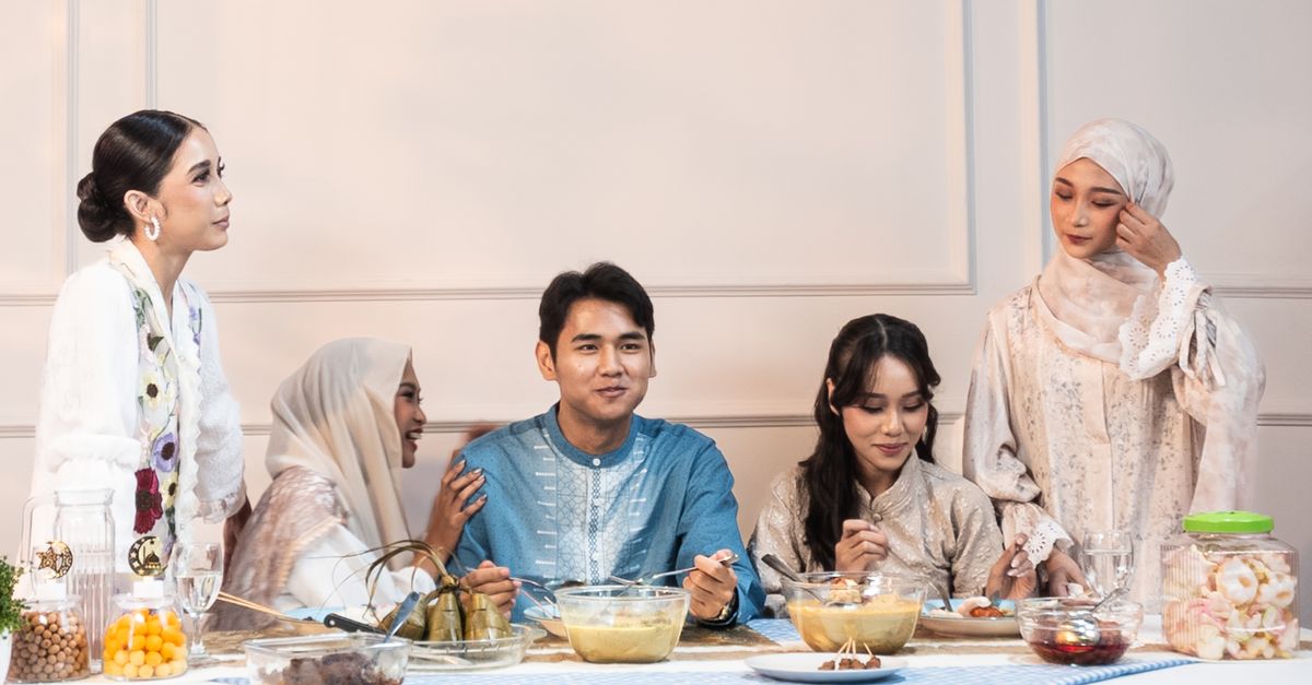 A joyful family enjoying a meal together indoors in traditional attire.