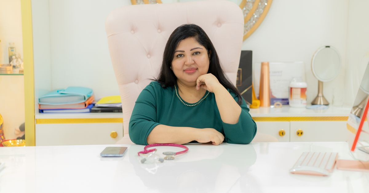 Confident woman seated at desk in a modern office, symbolizing professionalism and elegance.