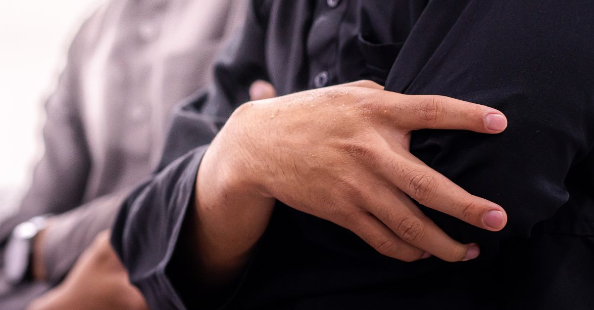 Focused image showing hands clasped in prayer during a religious gathering in an Indonesian mosque.
