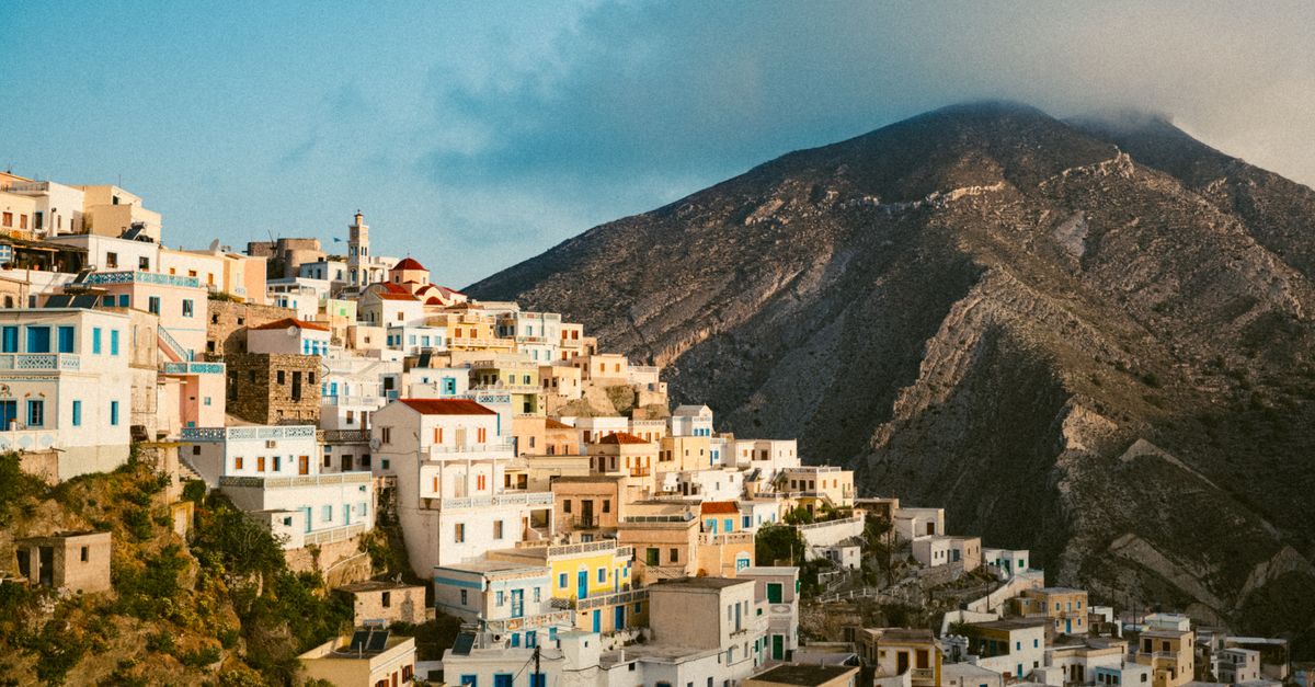 Scenic view of Olympos, Greece with colorful houses and a mountain backdrop.