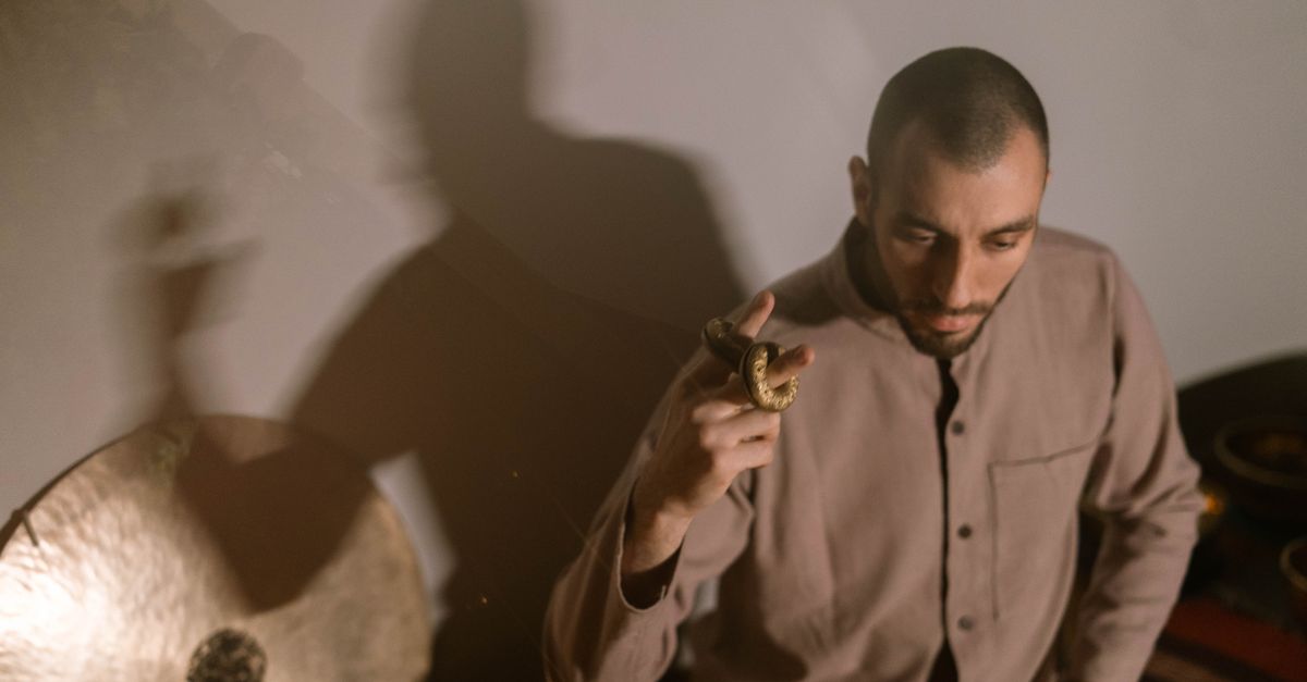 Meditative scene of a man using a gong and hudak to create relaxing sounds.