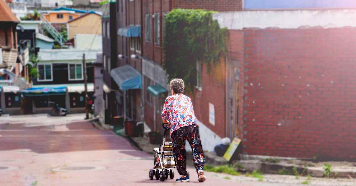 Senior woman with walker in colorful urban street, daytime.