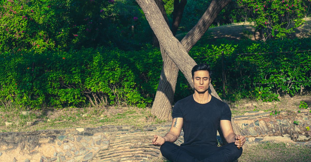 Man meditating peacefully in a lush Jaipur garden, embracing wellness and relaxation.
