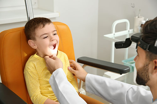 The image is showing an ENT specialist is diagnosing a kid with tonsils