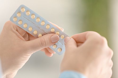 woman holding hormonal contraceptive pills in had