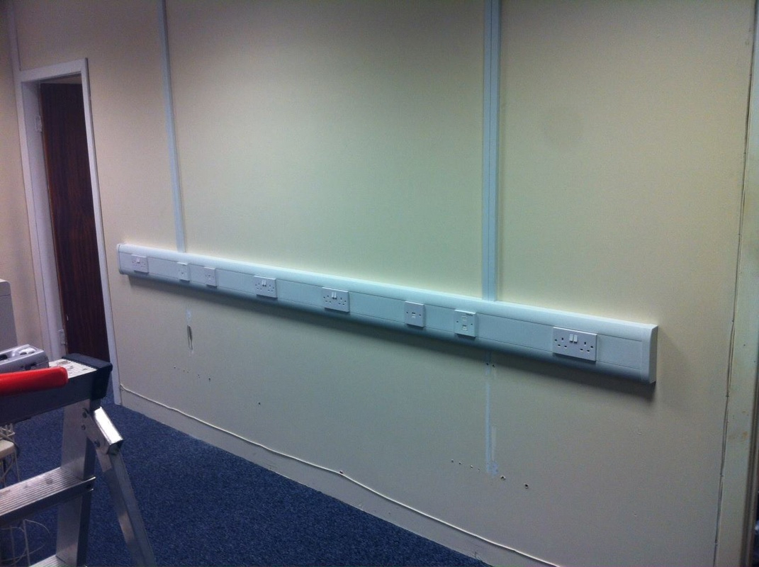 Self-adhesive cable trunking installed behind a living-room TV, ready to be painted to match décor.