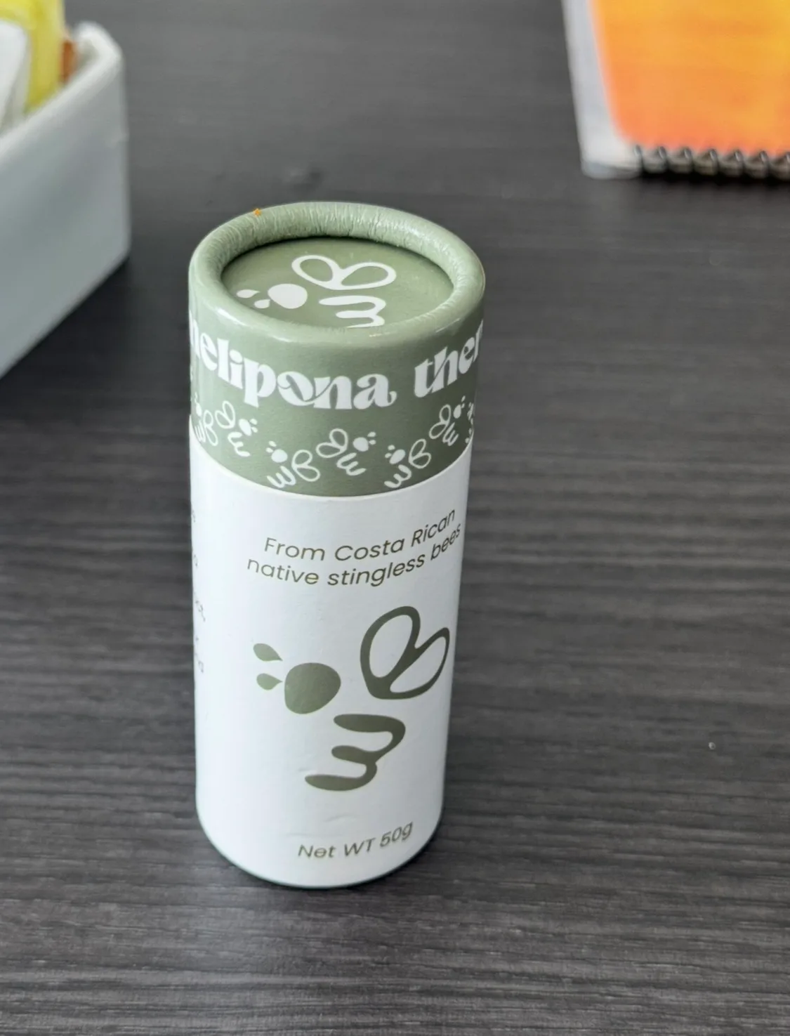 Envase cilíndrico de cartón verde con la marca Melipona Therapy, indicando que proviene de abejas nativas sin aguijón de Costa Rica.