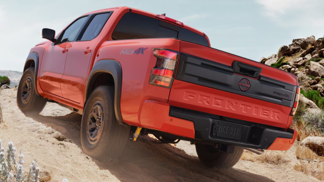 Vue arrière du Nissan Frontier 2025 sur chemin de sable en pleine puissance