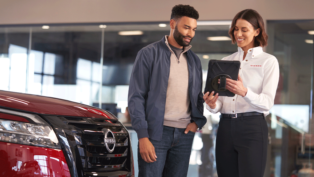 Vue d'un homme avec une femme au service à la clientèle Nissan, entrain de lui offrir le financement ou la location