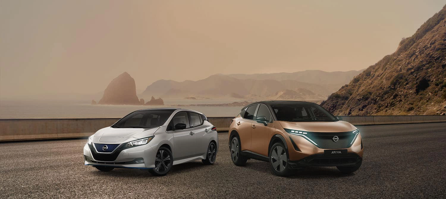 gamme de véhicules électriques nissan leaf voiture berline compacte et vus ariya 2023 sur une route en bordure de la mer au coucher de soleil