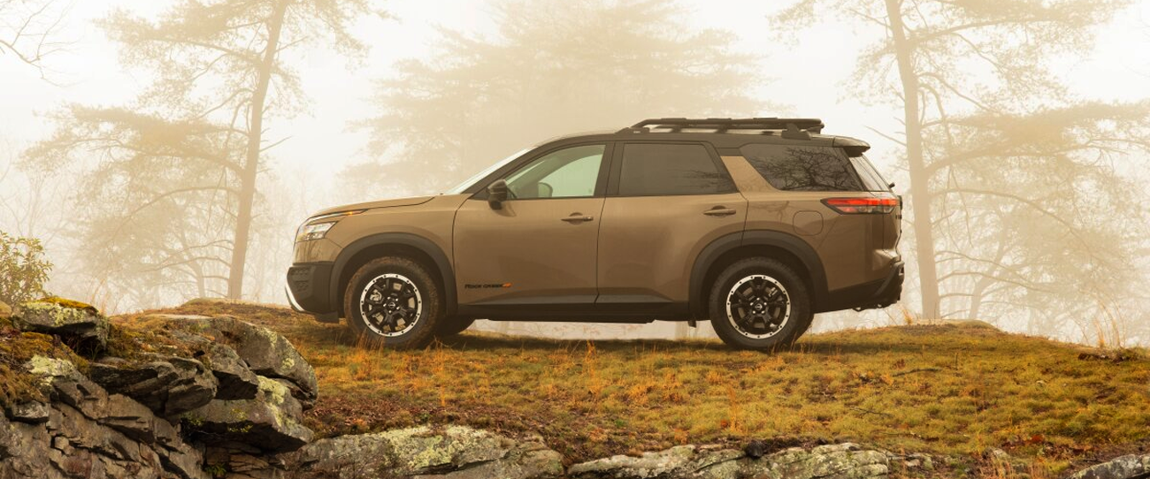 Vue latérale du Nissan Pathfinder 2025 en arrêt eb forêt avec brume matinal