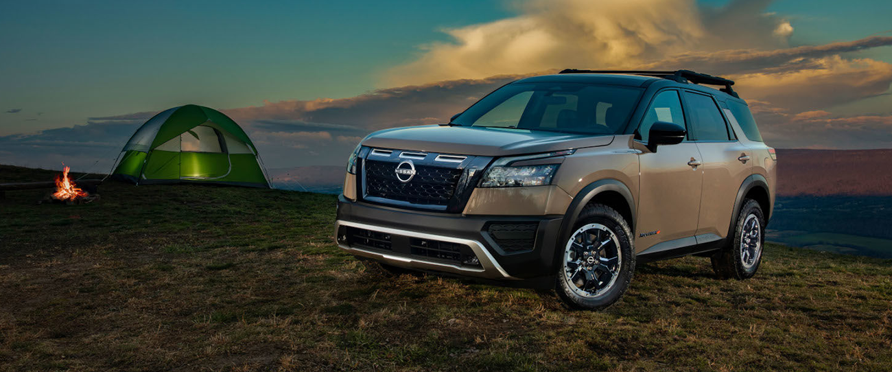 Vue 3/4 avant et latérale du Nissan Pathfinder 2025 en arrêt dans un champ avec espace de camping