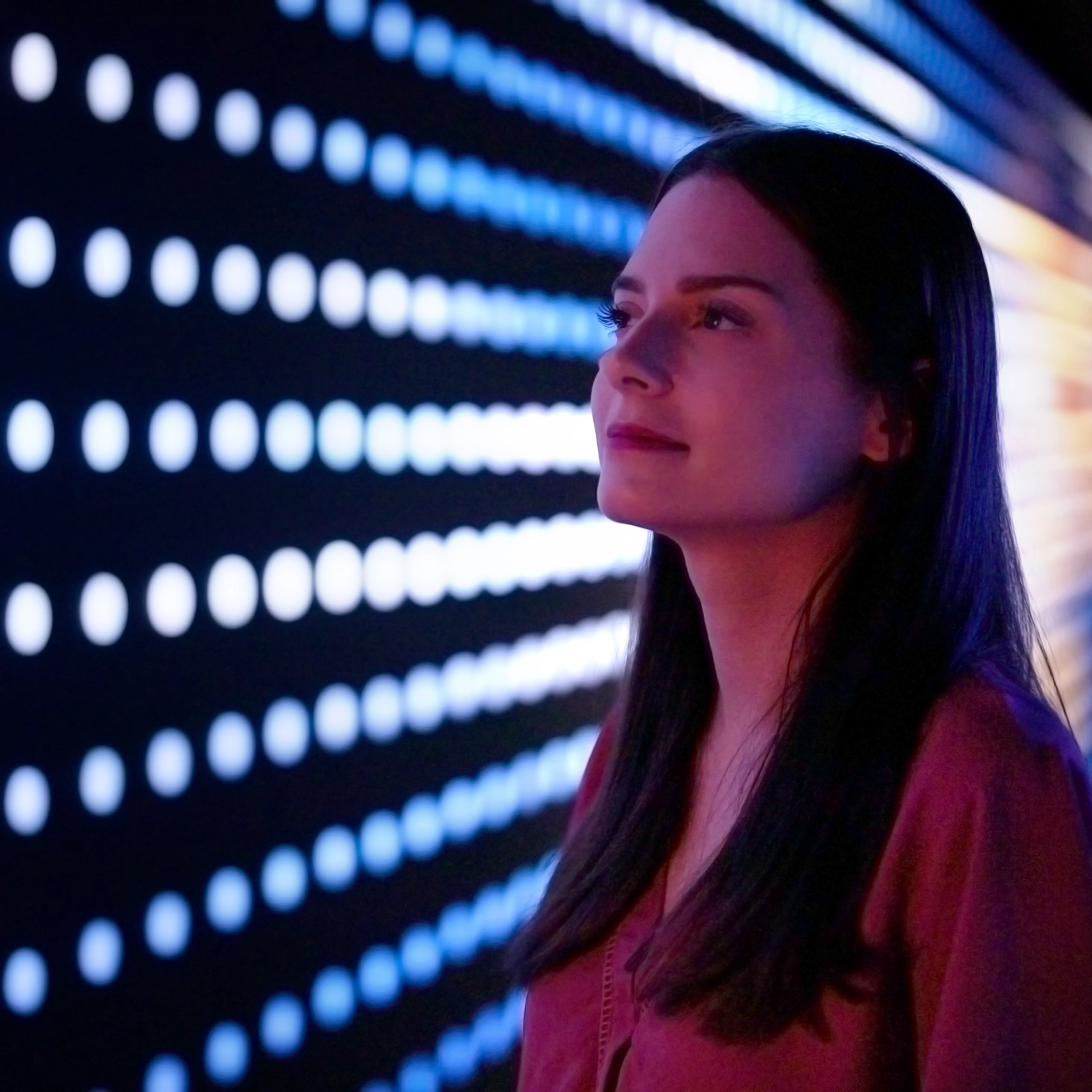 Woman observing grid array of animated lights in Lake Effect installation