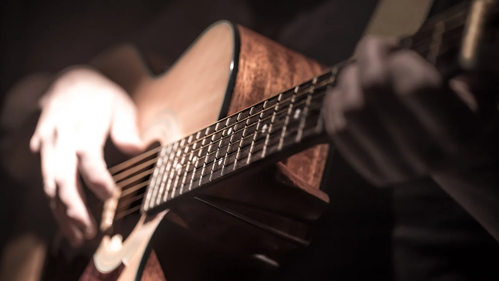 Nahaufnahme einer akustischen Gitarre und der Hände beim Spielen