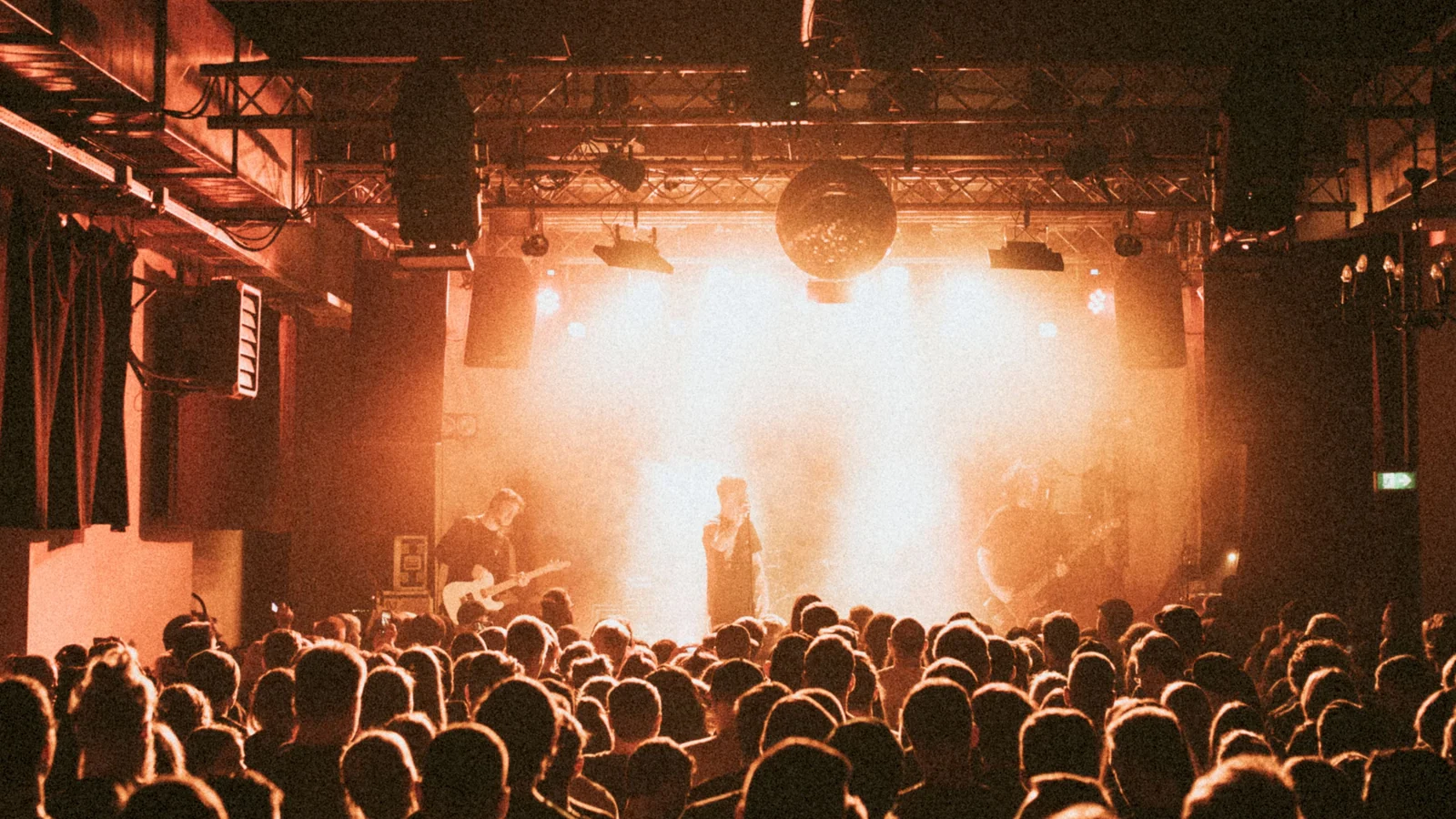 Publikum vor einer Band auf einer warm beleuchteten Konzertbühne.