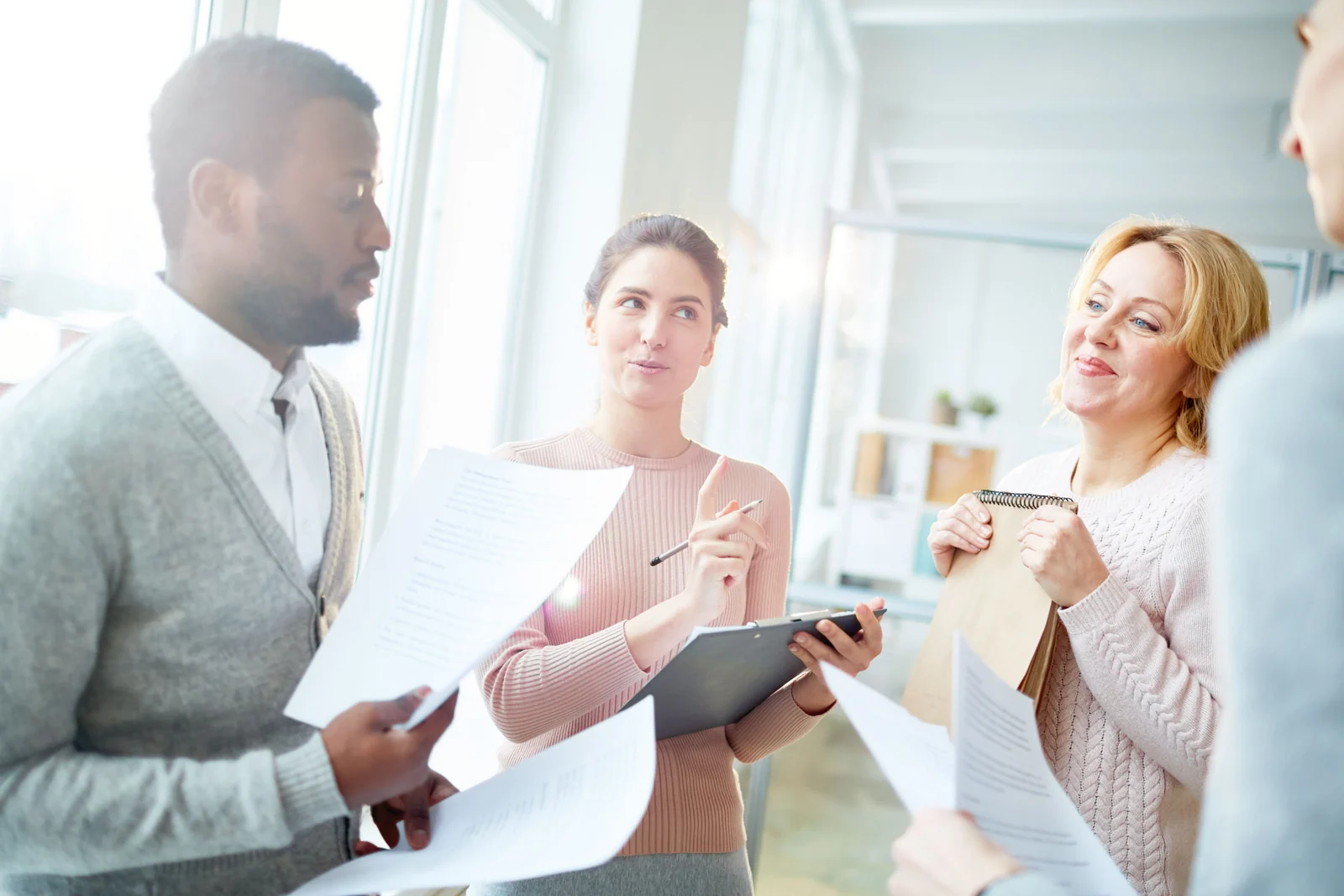 Vier Personen besprechen Unterlagen und machen Notizen in einem hellen Büro