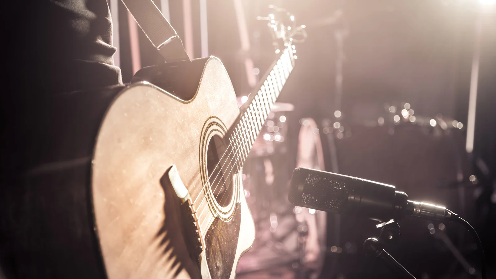 Akustische Gitarre vor einem Mikrofon im warmen Bühnenlicht