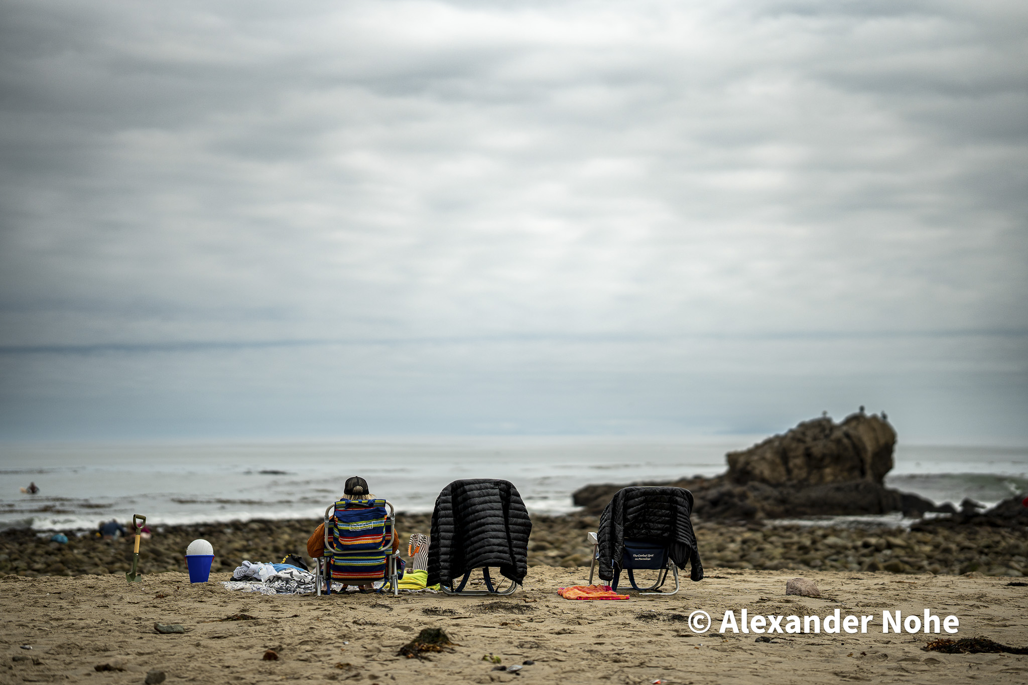 Beach chairs on a rocky shore facing the ocean