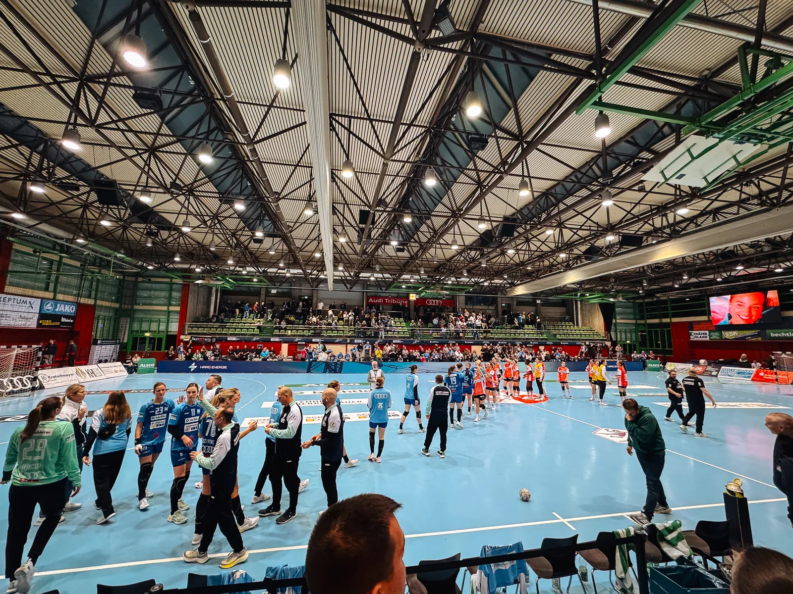 Blick in die Ballei in Neckarsulm: Handballfeld mit beiden Mannschaften und Zuschauern unter dem Hallendach