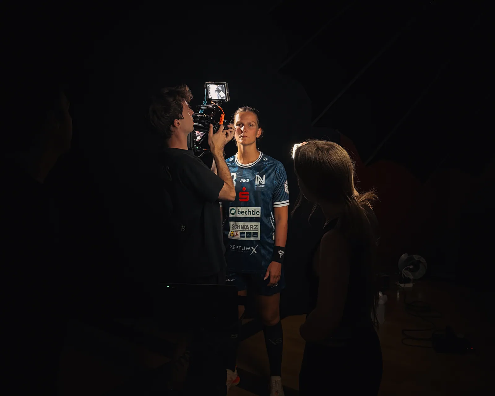 Kameramann filmt eine Spielerin der Sport-Union Neckarsulm im dunklen Set, daneben eine Kollegin