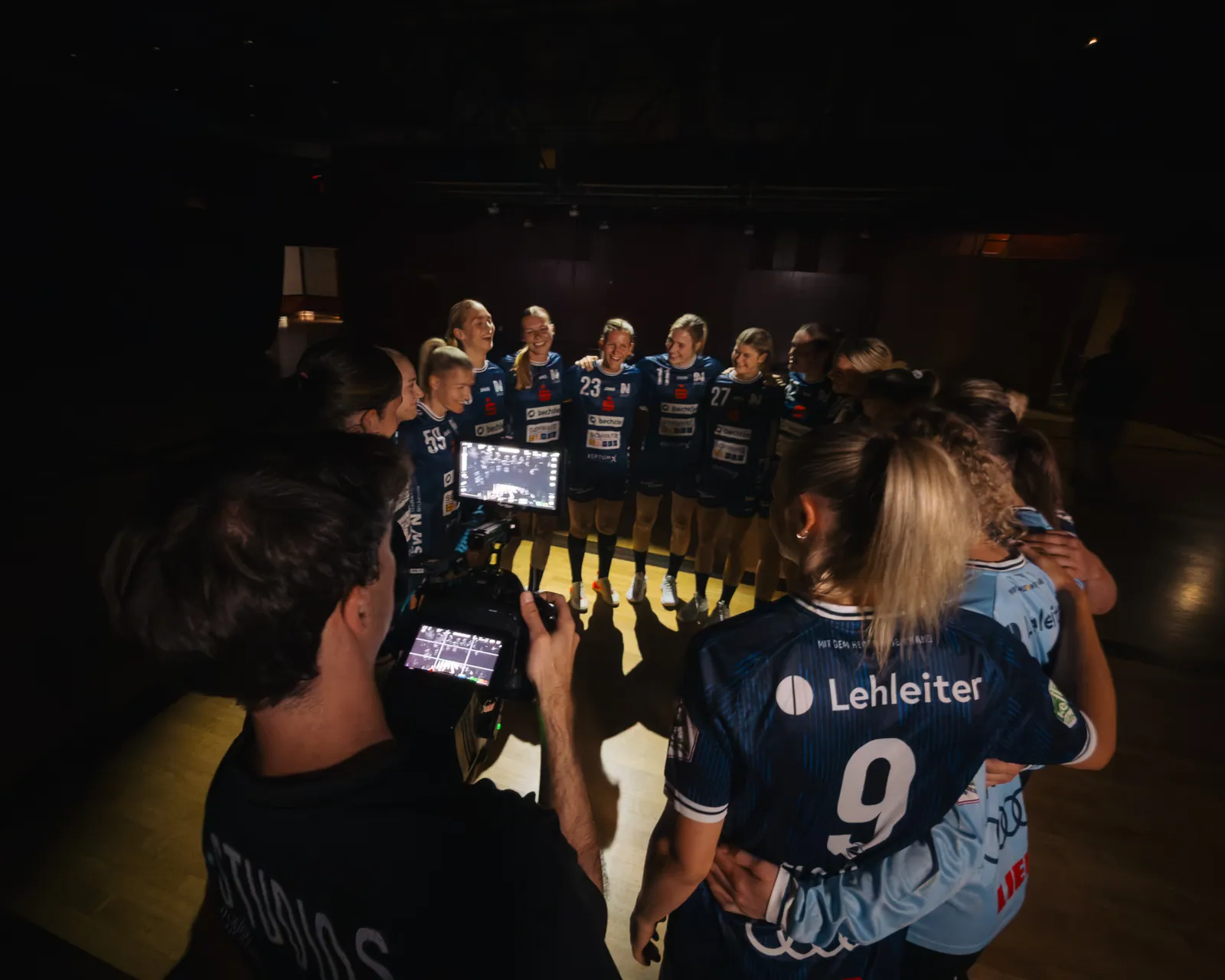 Kameramann mit Monitor filmt die Mannschaft, im Vordergrund eine Spielerin mit der Nummer 9
