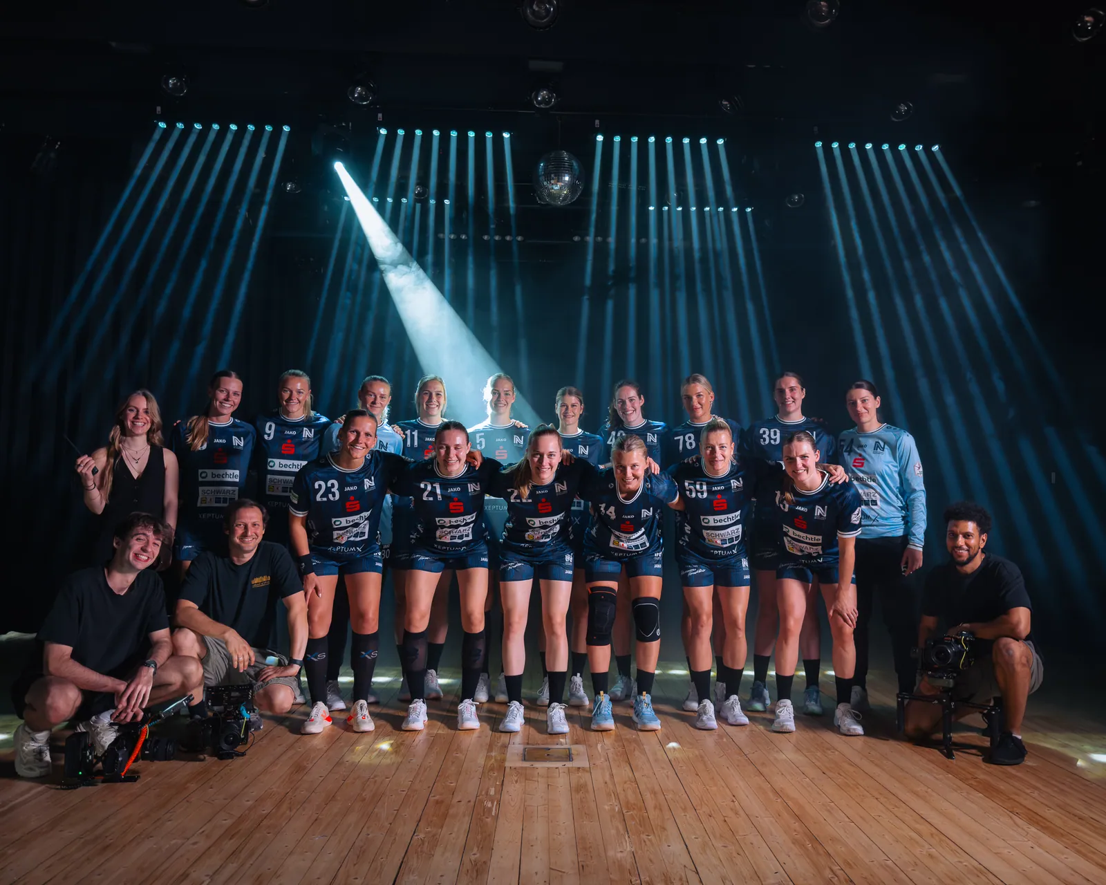 Mannschaft der Sport-Union Neckarsulm mit Drehteam vor Scheinwerferstrahlen in der dunklen Halle