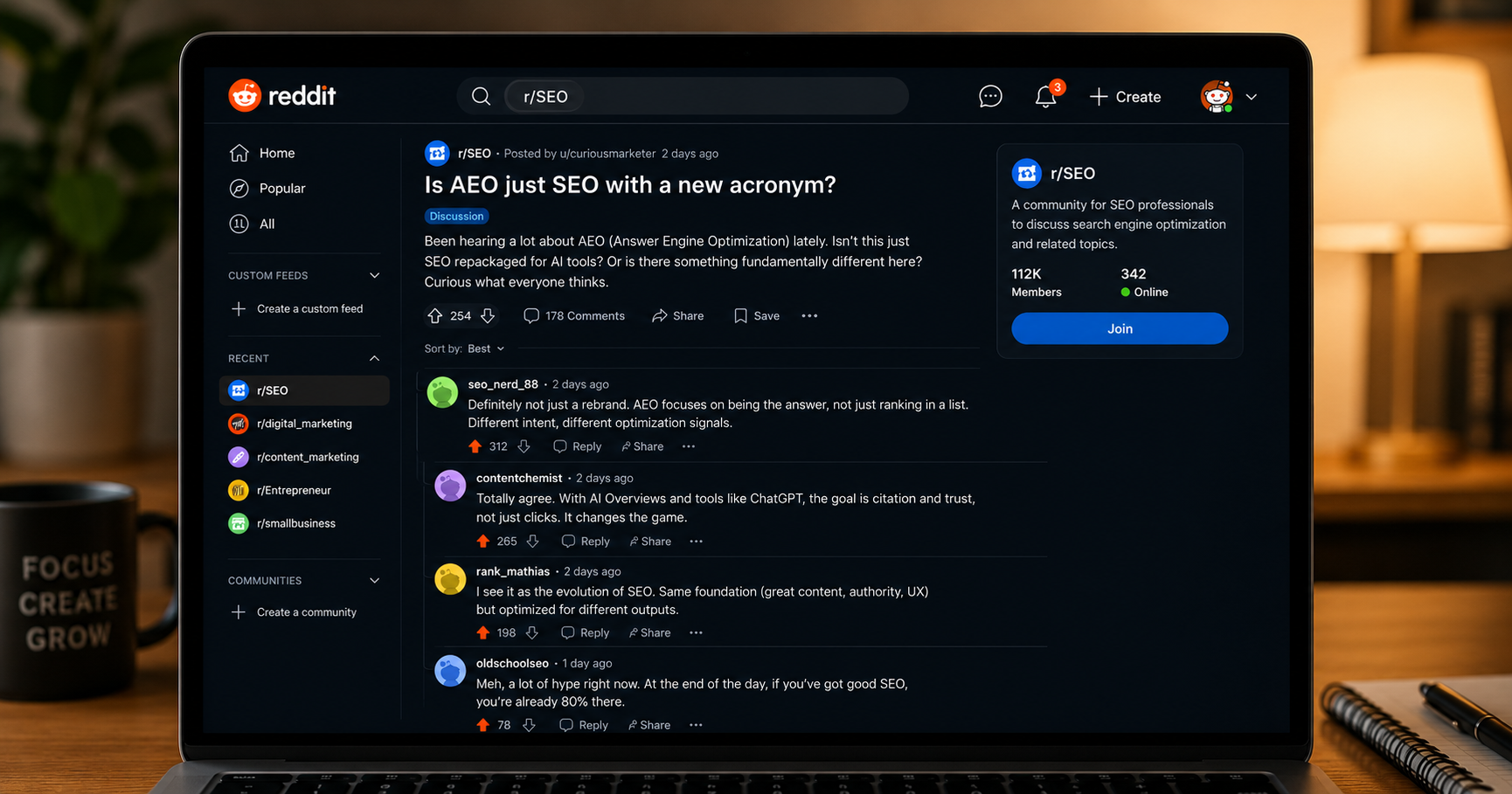 A laptop screen showing a Reddit thread titled "Is AEO just SEO with a new acronym?" with multiple upvoted replies visible below