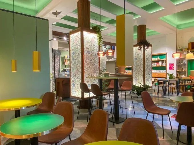 The image is well-lit with vibrant and accurate colors, effectively capturing the ambiance of the modern interior space. It presents a realistic view, highlighting key design elements. However, the composition is somewhat hampered by dominant, slightly out-of-focus foreground tables, and overall sharpness could be improved in both foreground and background elements.
