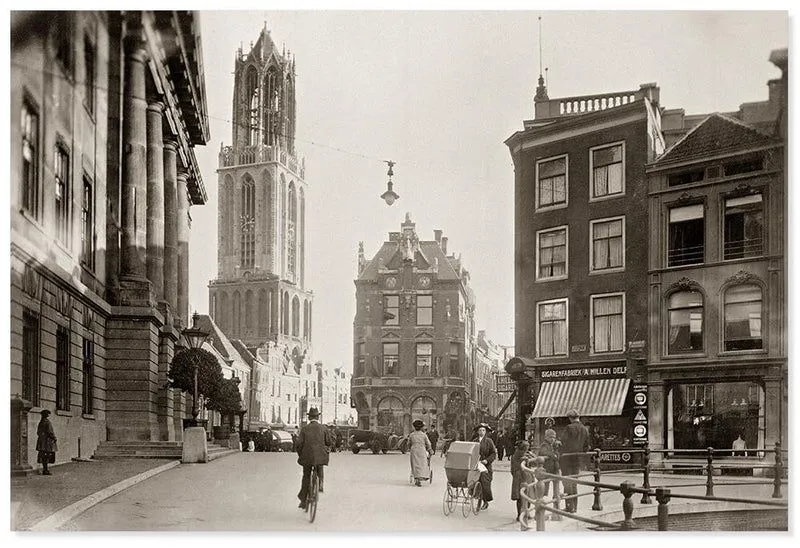 This is a well-composed historical photograph capturing a bustling street scene with a prominent tower. The lighting is even, and the image exhibits good tonal range for a black and white photograph. While not achieving modern levels of sharpness, the key elements are reasonably in focus given its age and photographic techniques. It is highly photo-realistic, accurately depicting the scene from its era.
