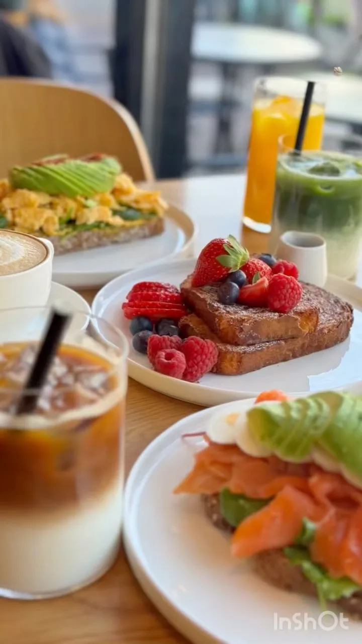 The image is well-lit and photo-realistic, showcasing vibrant and appetizing food. The key subject, French toast with berries, is sharp and in focus, with accurate colors. The composition is generally good, though the blurred foreground drink slightly detracts from the main subject by being partially in frame.