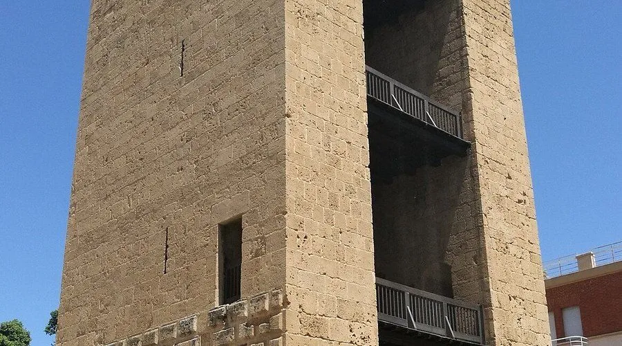 The image features a sharp, well-lit, and photo-realistic close-up of an old stone building facade with wooden balconies. The natural light highlights the texture of the stone, and all key elements are in clear focus. The colors are accurate, reflecting the natural hues of the materials.