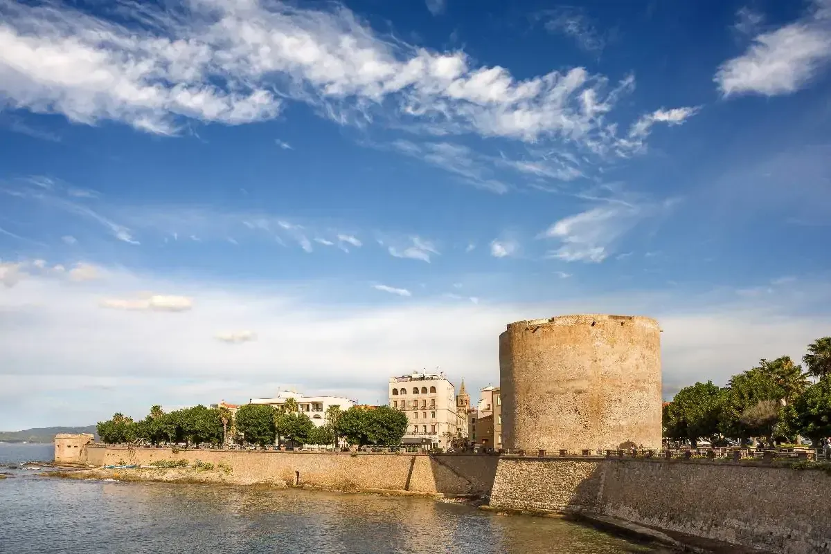 This image displays excellent quality across all criteria. The composition is well-balanced, highlighting the historical tower against a vibrant blue sky and waterfront. Lighting is superb, contributing to the photo-realistic appearance and accurate colors. The image is sharp throughout, with all key elements, especially the tower and surrounding architecture, clearly in focus.