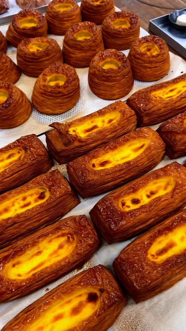 The image features an appealing arrangement of golden-brown pastries with a bright yellow filling, showcased in a well-composed shot. The lighting is excellent, highlighting the flaky textures and vibrant colors. The pastries are sharp, particularly those in the foreground, and the overall photo-realism is high, making the food look very appetizing.