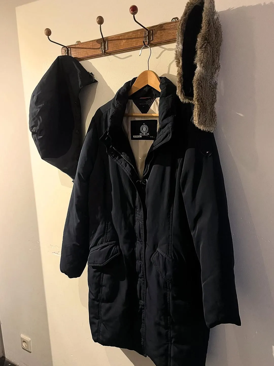 A dark blue winter coat is clearly displayed, showing its texture and design, though the lighting is uneven.