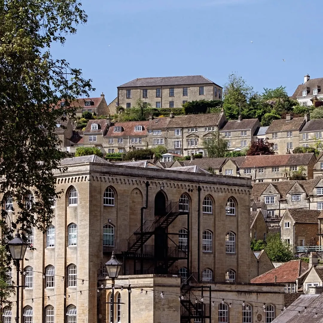 A scenic view of a historic town built on a hillside, featuring stone buildings under a clear blue sky.