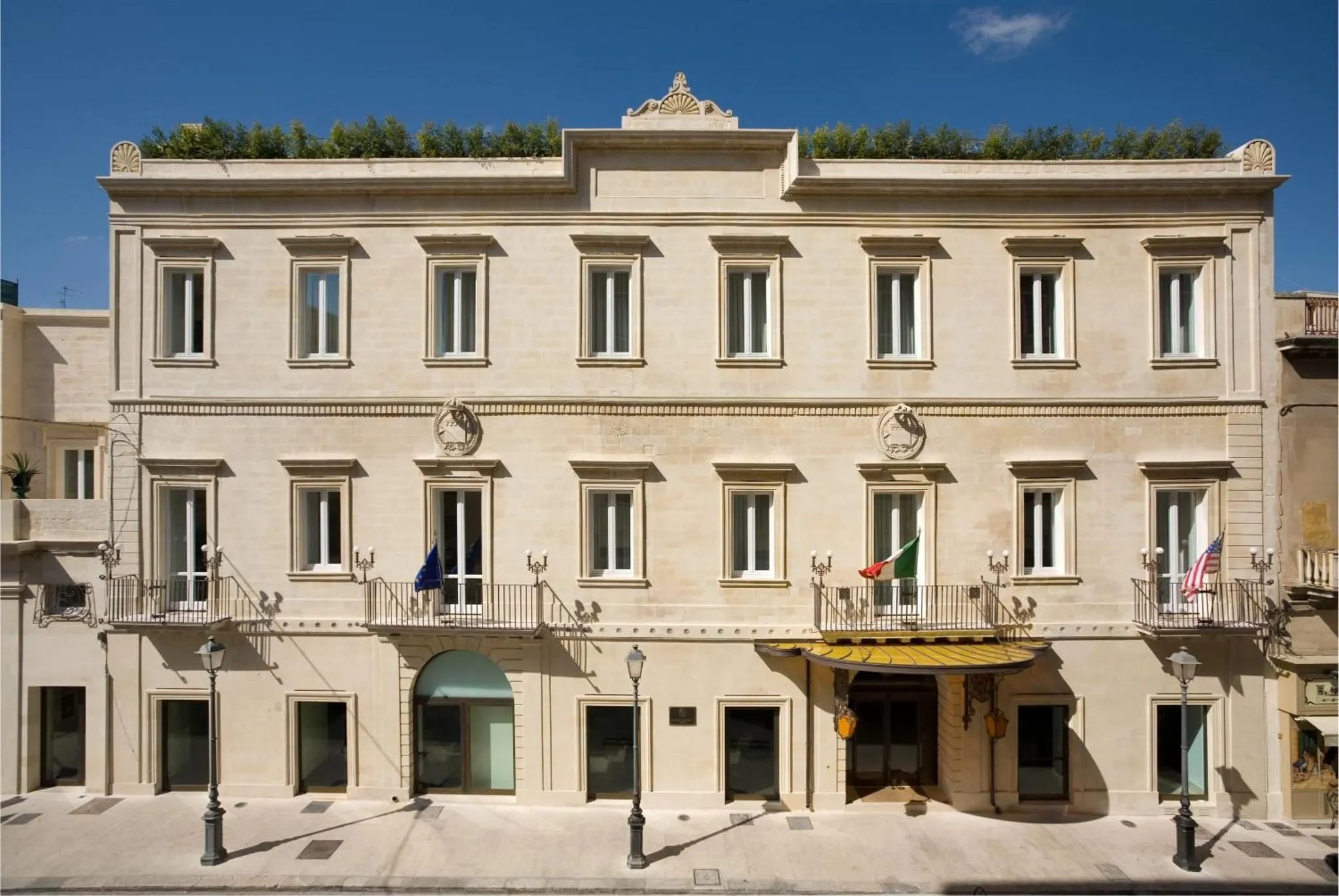 A well-composed, brightly lit image of a building facade under a clear blue sky. The image features clean lines, sharp details, and accurate colors, effectively capturing the architectural elements.