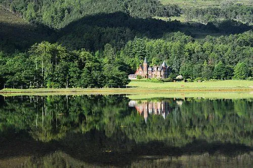 An editorial quality image showcasing a grand building nestled amidst lush green trees, perfectly reflected in a still body of water. The scene is bathed in natural light, highlighting the vibrant colors and intricate details.